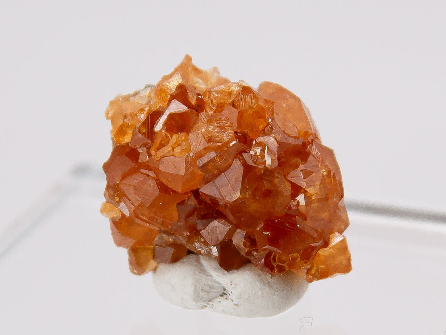 Orange crystal cluster of spessartine garnet on a white background.