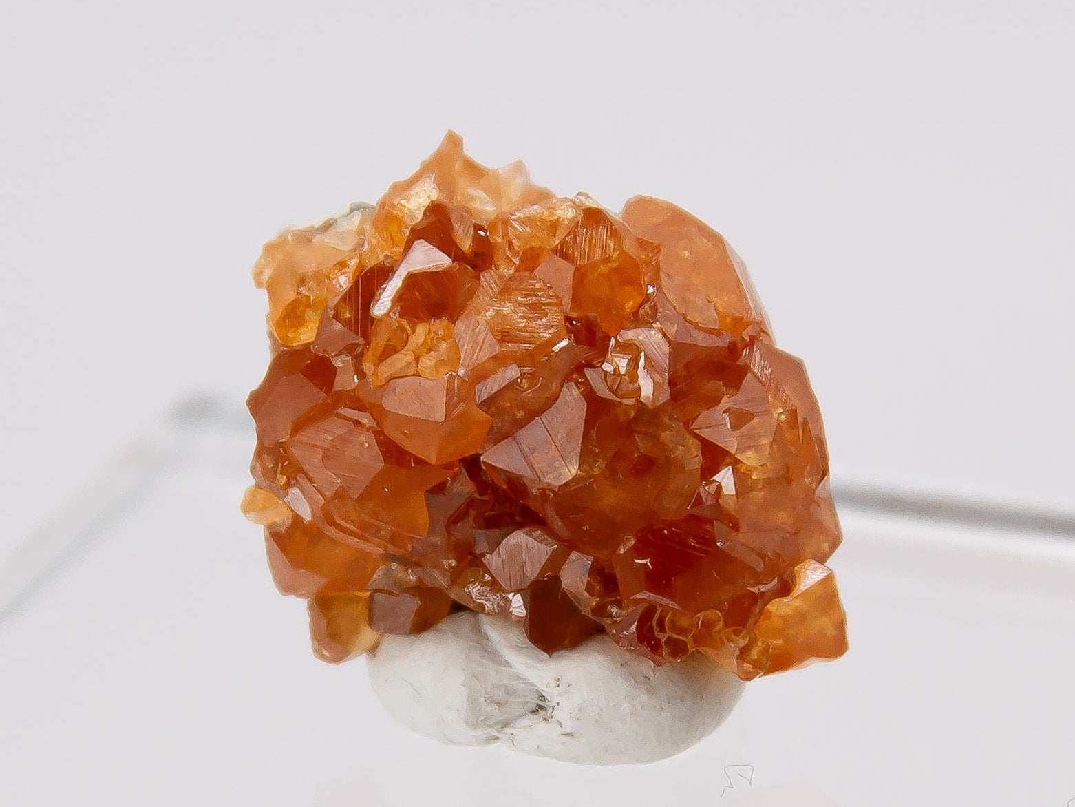 Orange crystal cluster of spessartine garnet on a white background.