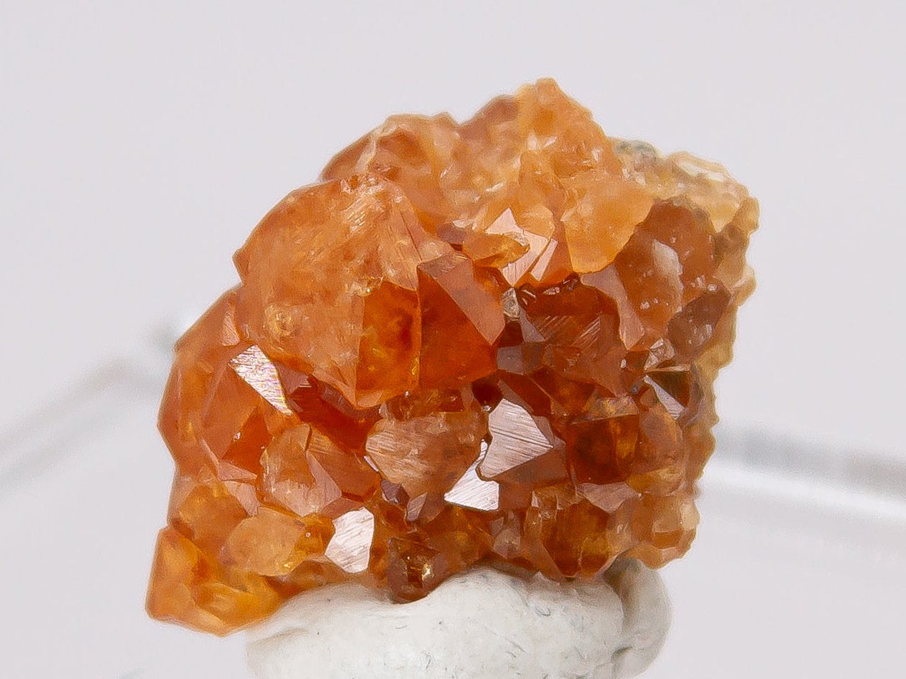 Close-up of an orange crystal cluster of the mineral garnet on a white background.