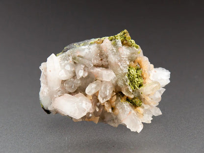 White quartz with epidote crystals on a gray background, labeled 'Adamantine Minerals'