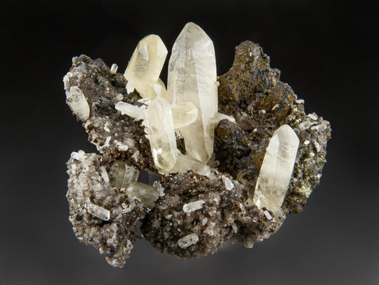 Sweetwater calcite specimen with small cream-colored dolomite crystals and brassy chalcopyrite on a gray background.