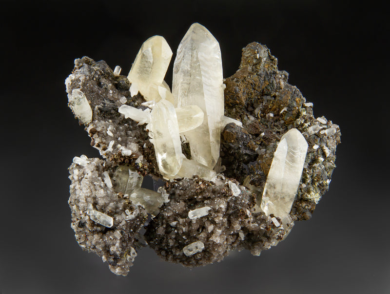 Sweetwater calcite specimen with small cream-colored dolomite crystals and brassy chalcopyrite on a gray background.