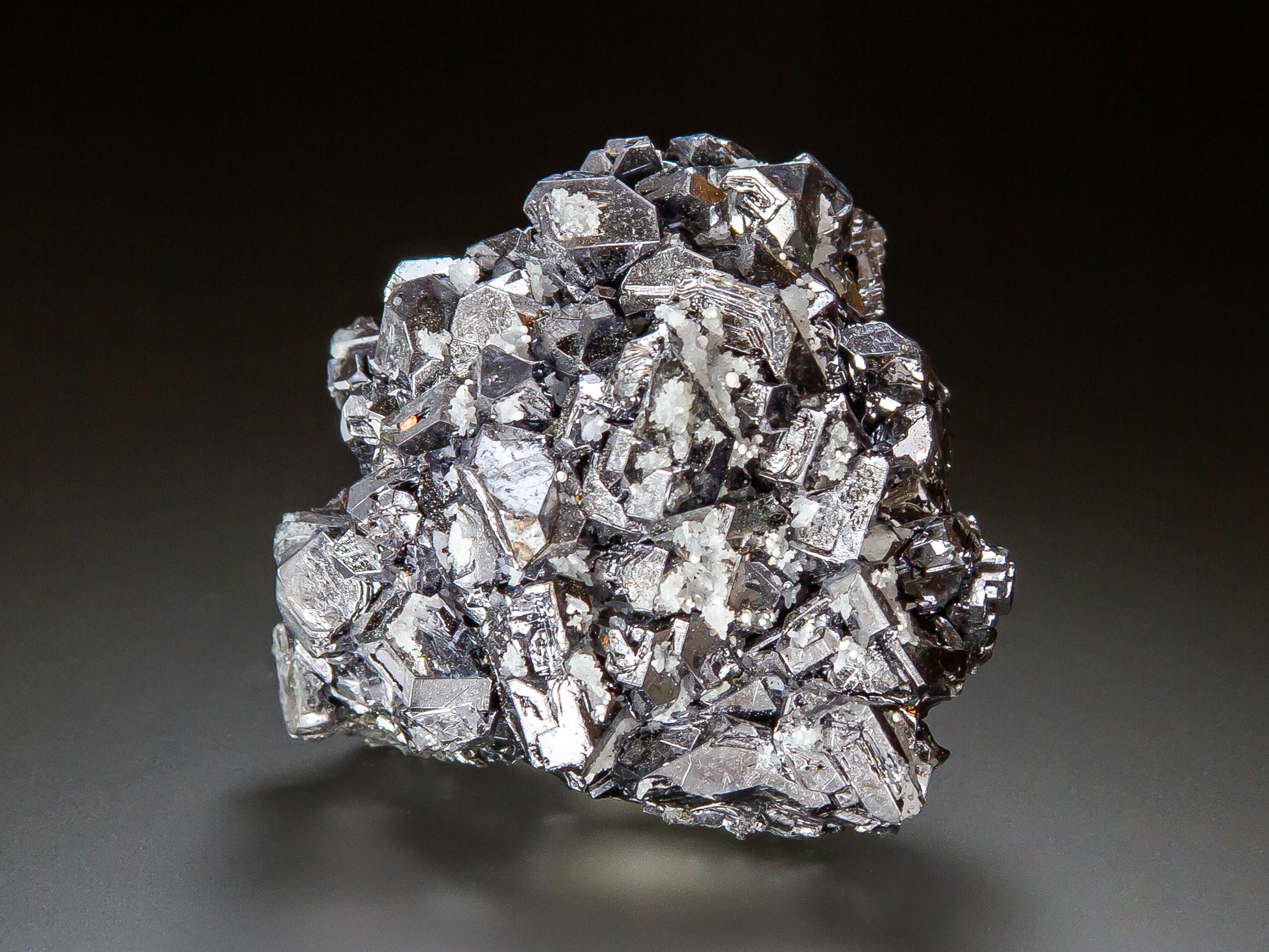 A metallic silver crystal cluster of galena, photographed on a dark gray to black gradient background.