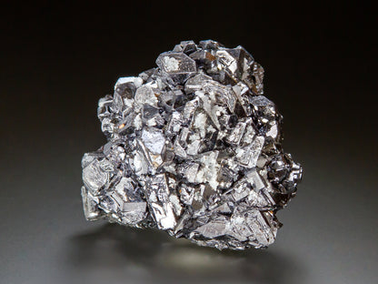 A metallic silver crystal cluster of galena, photographed on a dark gray to black gradient background.